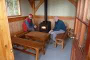Two volunteers test the woodstove at the new hut built by Dave Watson, Bob McQueen and their crew of helpers...